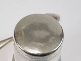 a silver tea pot with a spoon on a white plate
