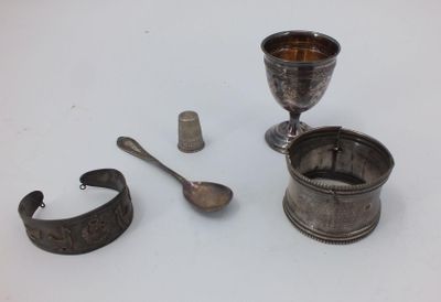 a silver cup, spoon, and other items on a white surface