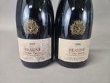 two bottles of red wine sitting next to each other on a table