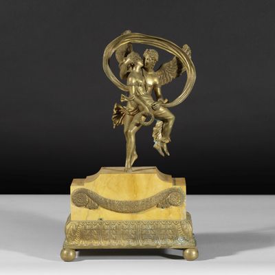 une figurine antique en bronze représentant un Cupidon tenant un oiseau