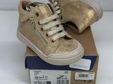 the children ' s gold sneakers are on top of a cardboard box