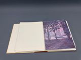 an open book sitting on top of a table with a painting on it