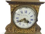 a gold clock with blue roman numerals on the face