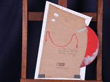a picture of a piece of paper and a red disk on a wooden easer