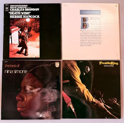 quatre albums de styles musicaux variés sont posés sur une surface blanche