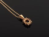 a gold necklace with a flower pendant on a black surface