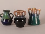 three different colored vases sitting next to each other on a white surface