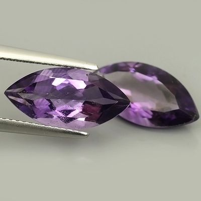 Des pierres précieuses d'améthorate violettes sont vendues à l'aide d'une paire de pinces.