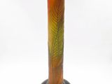 an orange and green vase sitting on top of a black base
