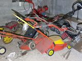 many lawn mowers and other lawn equipment in a garage