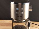 the coffee maker is sitting on a wooden table with a black background