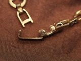 a gold bracelet with a lock on it on a brown cloth