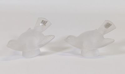 une paire de figurines de poissons en verre transparent posées sur un fond blanc