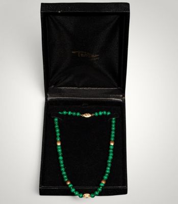 a green beaded necklace in a black box with a gold clasp