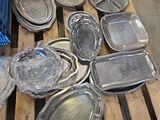 de nombreux plateaux en argent posés sur une palette dans un entrepôt