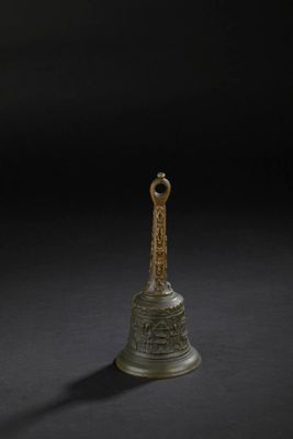 une cloche en bronze sur fond noir, avec une ombre
