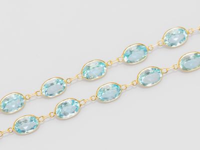 a close up of a gold chain with blue topaz beads