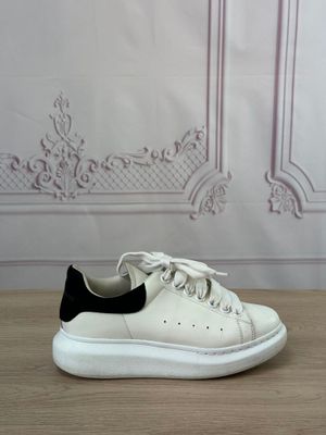 white and black sneakers on a wooden table in front of a wall