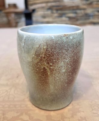 un gros plan d'une tasse posée sur une table, avec un mur en pierre en arrière-plan