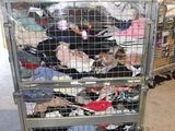 a metal cart filled with lots of clothes in a warehouse