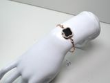 une main de mannequin blanche ornée d'un bracelet noir et doré