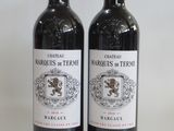 two bottles of red wine sitting next to each other on a table
