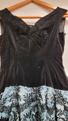 une robe noire et bleue suspendue à un cintre devant un mur blanc