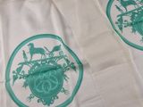 deux serviettes blanches ornées de motifs verts, posées sur une table