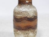 un vase brun et blanc posé sur une surface blanche