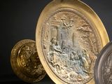 two gold and silver plates sitting on top of a black surface