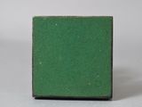 a small square green tile on a white surface