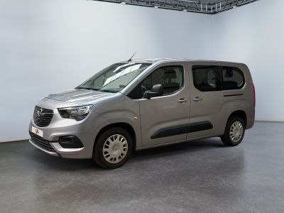 La camionnette argentée est garée dans une grande pièce aux murs blancs.