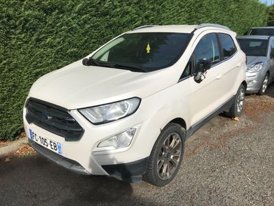une voiture blanche garée sur un parking, à côté d'une haie