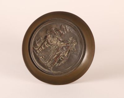 an antique bronze plate with an image of a man riding a horse