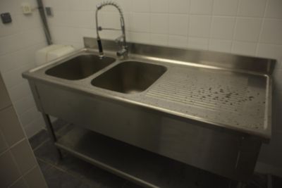 un lavabo en acier inoxydable équipé d'un robinet, situé dans des toilettes publiques