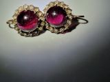a close up of a pair of earrings on a white surface