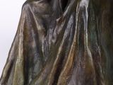 statue of a woman sitting on a chair with a blanket on her back