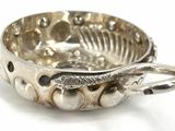 a silver bowl with a spoon in it on a white surface
