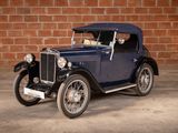 a vintage car that is parked in front of a brick wall