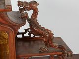 a statue of a dragon sitting on top of a wooden shelf