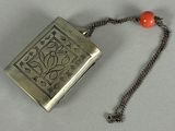 a silver purse with a red bead on a chain