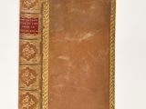 a brown book with gold trim sitting on a white surface
