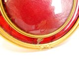 a picture of a picture of a red and gold broochle