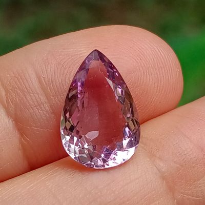 someone is holding a pink diamond in their hand on a green background