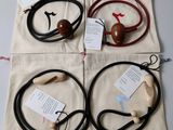 three pairs of headphones with cords and a bag on a table