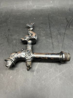 a metal faucet that has a bird on it