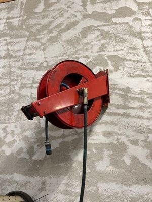 une lance à incendie rouge fixée au mur à côté d'une horloge