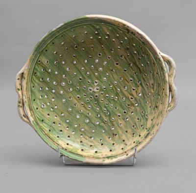 green and white ceramic bowl with holes in the center