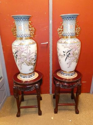 deux vases posés sur un petit tabouret devant un mur rouge
