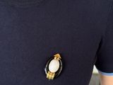 a close up of a person wearing a black sweater and a white broocher